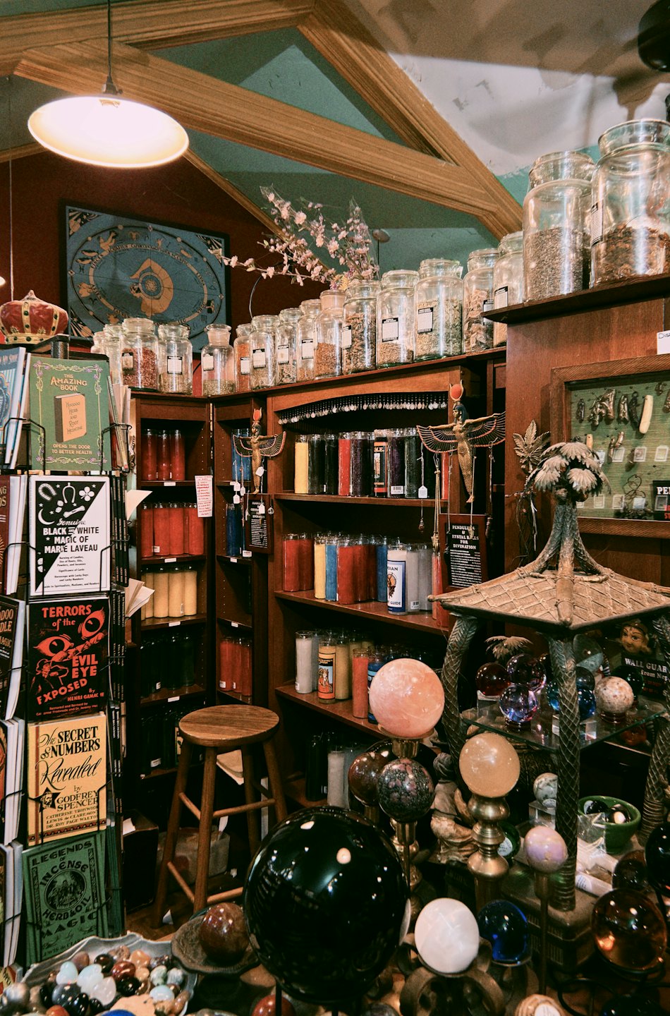 Estanterías de madera repletas de hierbas, velas y libros de ocultismo.